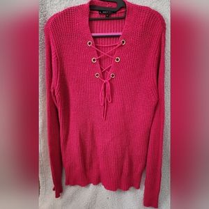 Women's knit sweater with lace up front and rhinestone embellished grommets.